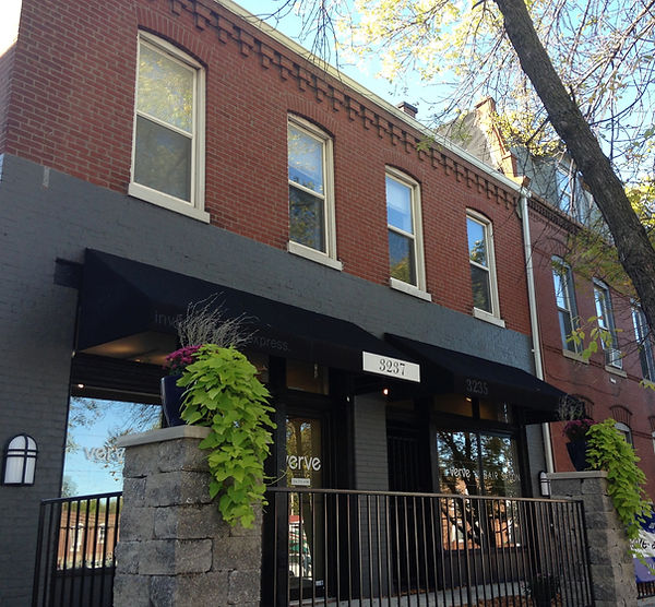 Red brick storefront with black awnings and the number 3237 above the door
