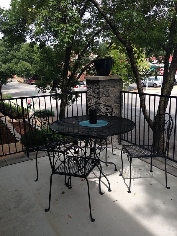 Black wrought iron table and chairs on a shaded patio by the street