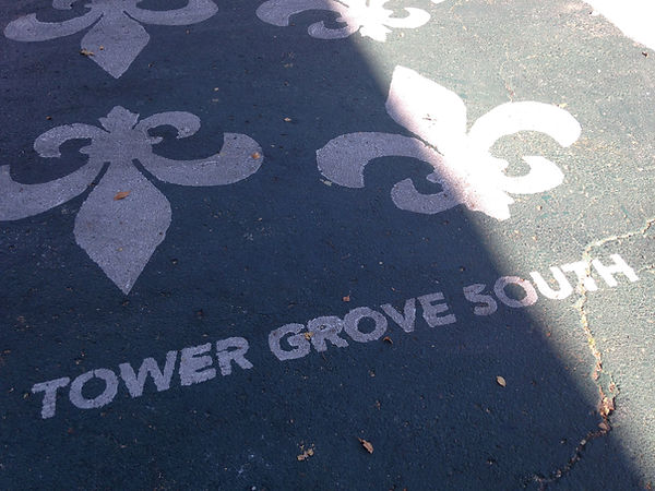 Fleur de lis shapes and the words Tower Grove South painted on the sidewalk